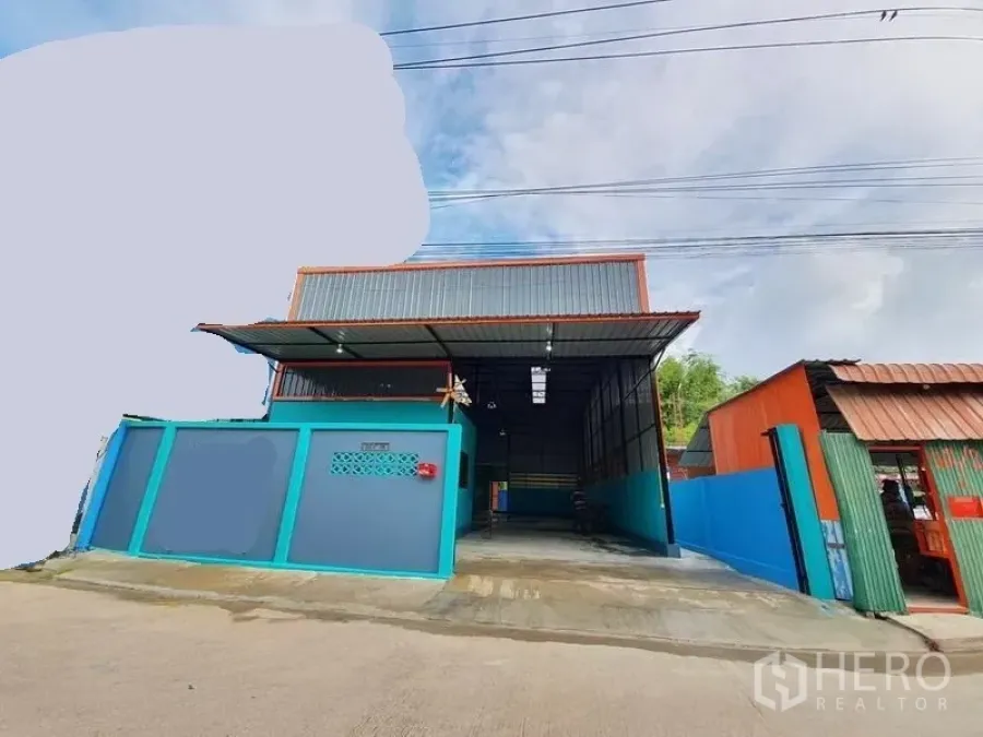 คลังสินค้า ให้เช่าในNonthaburi - มุมมองด้านหน้าโกดัง มีประตูรั้ว หลังคากันสาดโลหะ และทางเข้าคอนกรีต