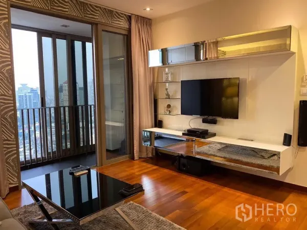 Condominium for rent in Khlong Toei, Bangkok - Sleek media wall with mounted TV and shelving beside glass doors opening to a balcony and skyline.