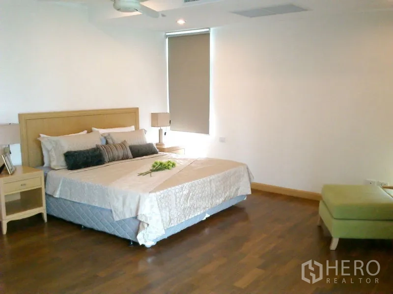 Condominium for rent in Khlong Toei, Bangkok - Large master bedroom with king bed, green chaise lounge and hardwood floors.