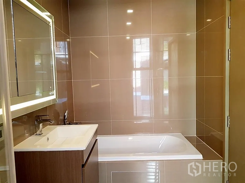 คอนโด ให้เช่าในWatthana, Bangkok - ห้องน้ำมีอ่างอาบน้ำ เคาน์เตอร์อ่างล้างหน้า และกระจกไฟ LED โทนอุ่น