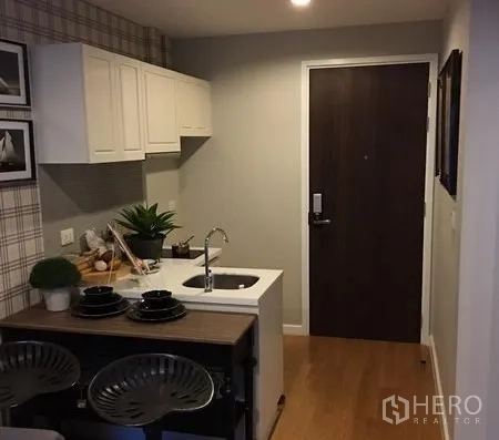 Condominium for rent in Khlong Toei, Bangkok - Compact entryway kitchenette with white cabinets, sink island, and wooden flooring in a Bangkok condo.