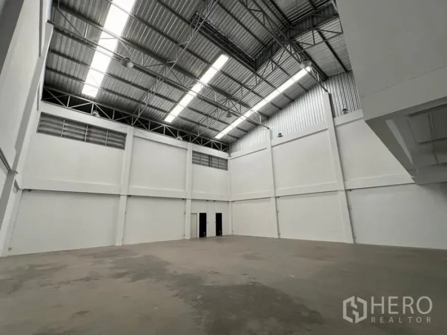 Warehouse for rent in Phra Samut Chedi, Samut Prakan - Clean white warehouse hall with tall walls and polished concrete floor.