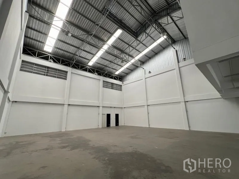 Warehouse for rent in Phra Samut Chedi, Samut Prakan - Clean white warehouse hall with tall walls and polished concrete floor.