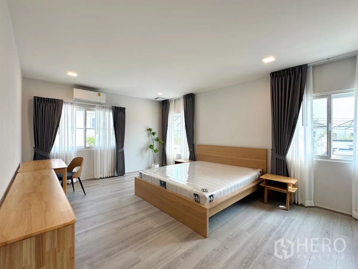 独立式住宅 出租在Bang Phli, Samut Prakan - 宽敞主卧，多个窗户、空调与浅木色家具