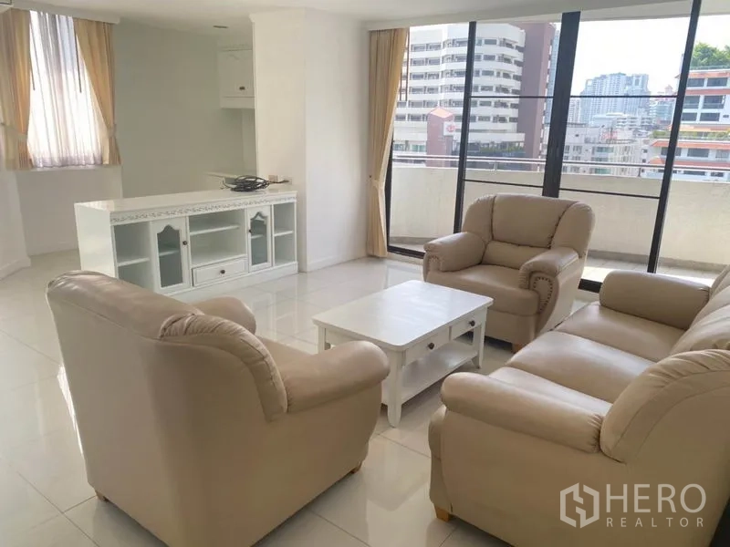 Condominium for rent in Watthana, Bangkok - Bright living room with beige sofa set, white TV console and large balcony doors overlooking the city.