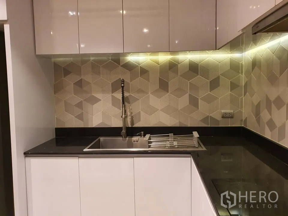 Condominium for rent in Watthana, Bangkok - Close-up of kitchen sink, under-cabinet lighting and patterned geometric backsplash tiles.