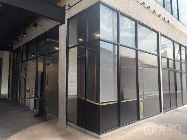 零售空间 出租 - 转角店铺，落地玻璃与黑色金属框，带有遮棚走道