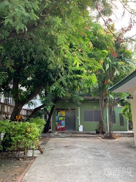 独立式住宅 出租在Khlong Toei, Bangkok - 长车道，两侧绿荫，后方有独立小建筑。