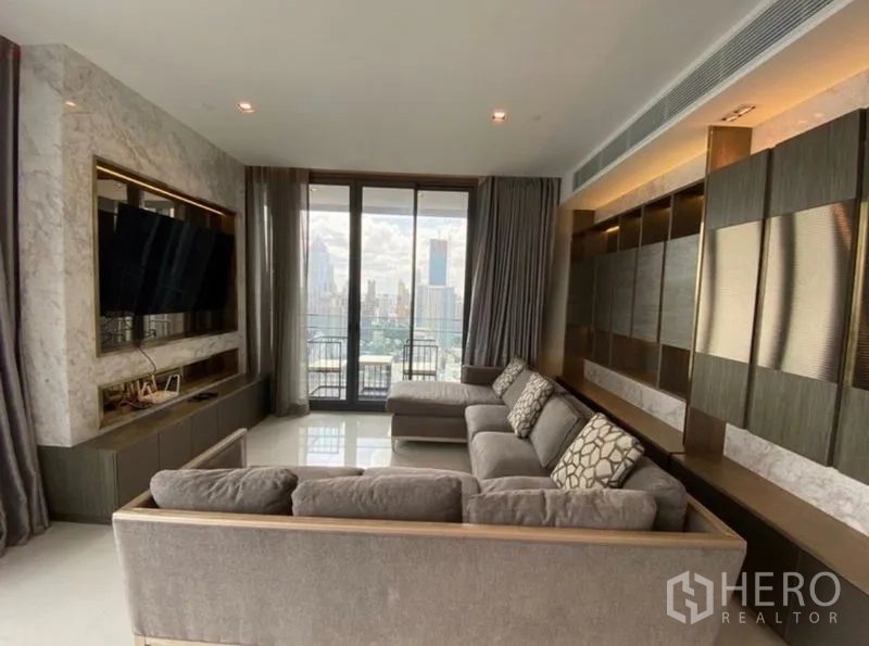 Condominium for rent in Khlong Toei, Bangkok - Contemporary living room with large sectional sofa, marble TV wall and balcony city view.