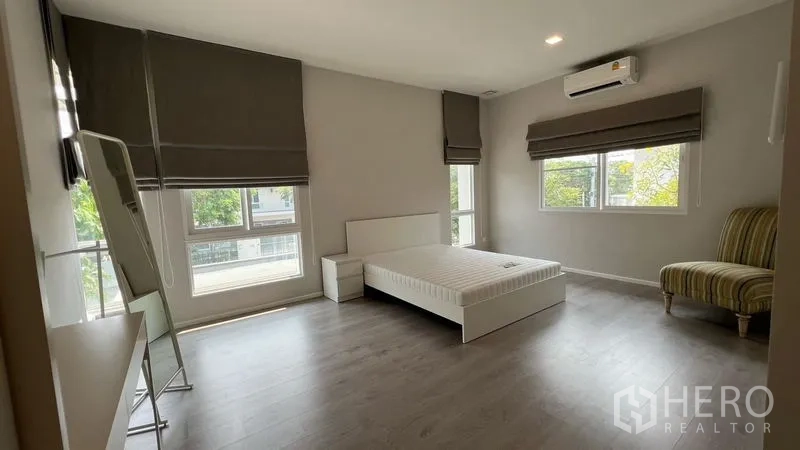 Detached House for rent in Prawet, Bangkok - Large secondary bedroom with big windows, air conditioning and minimalist furnishings.
