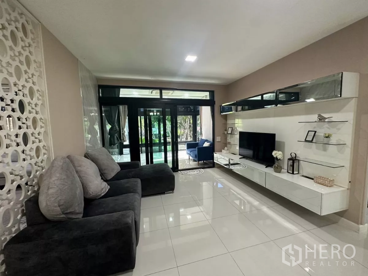 Detached House for rent or sale in Bang Kapi, Bangkok - Family living area with deep sofas, floating TV cabinet and garden views.