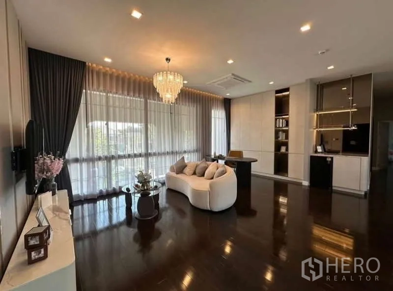 独立式住宅 出租在Lat Krabang, Bangkok - 二楼会客区，吊灯、弧形沙发、内置柜与落地窗。