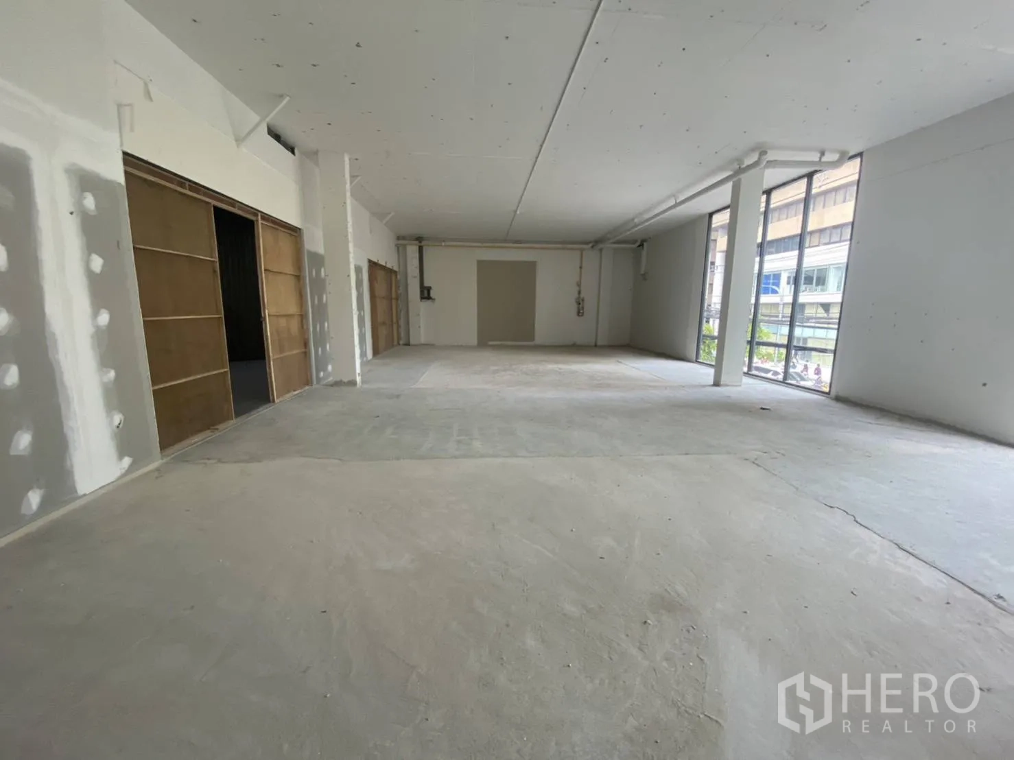 Retail Space for rent - Bright retail interior with unfinished walls, wide frontage, and tall glass panels facing city views, ready for custom fit-out.