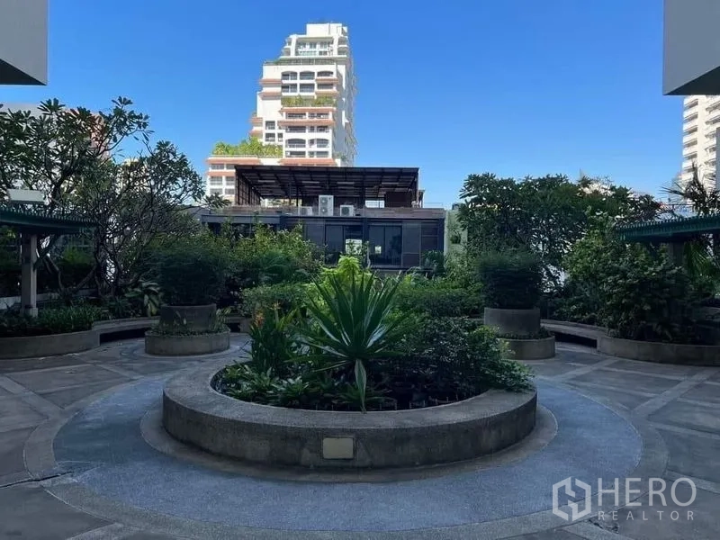 Condominium for rent or sale in Watthana, Bangkok - Landscaped communal courtyard garden with circular planter and city backdrop.