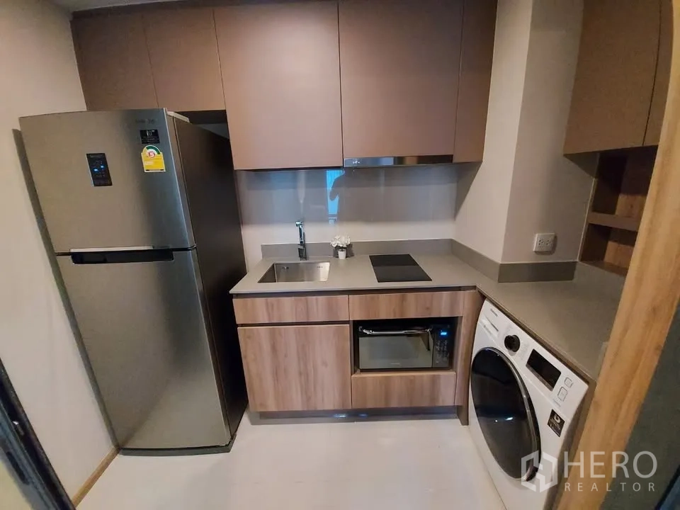 公寓 出租在Watthana, Bangkok - 封闭式小厨房，配冰箱、灶台、水槽、微波炉和洗烘一体机。