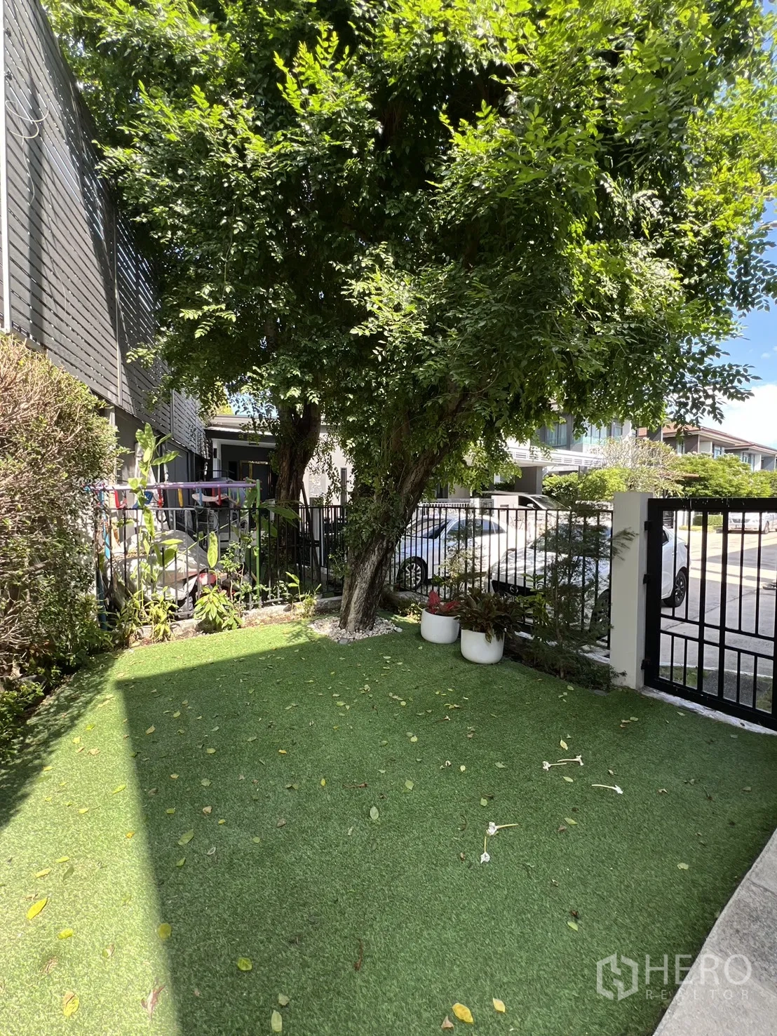 Detached House for sale in Bang Kapi, Bangkok - Shaded front lawn with a mature tree, planters, and gate.
