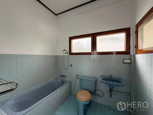 Detached House for rent in Watthana, Bangkok - Vintage bathroom with blue bathtub, toilet and sink beneath frosted windows.