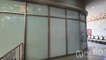 零售空间 出租在Khlong Toei, Bangkok - 室内走道旁的弧形转角玻璃店面，连续大幅窗。