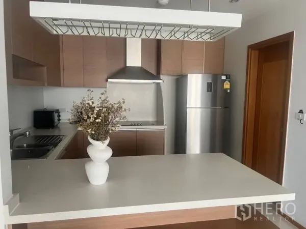 公寓 出租在Bangkok - 现代开放式厨房，木质柜体、不锈钢油烟机与冰箱，白色中岛。