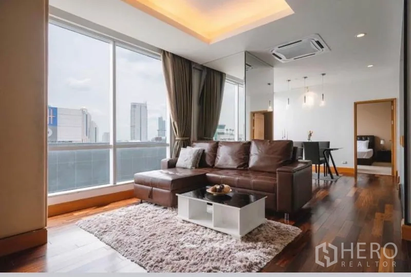คอนโด ให้เช่าในSathon, Bangkok - ห้องนั่งเล่นสว่างด้วยหน้าต่างกระจกเต็มบาน โซฟาหนังสีน้ำตาล เพดานหลุม พื้นไม้ และวิวเมือง