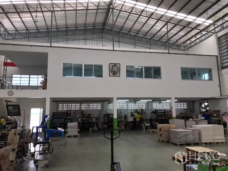 Factory for sale in Pak Kret, Nonthaburi - Wide interior view of the warehouse with steel truss roof and mezzanine offices.