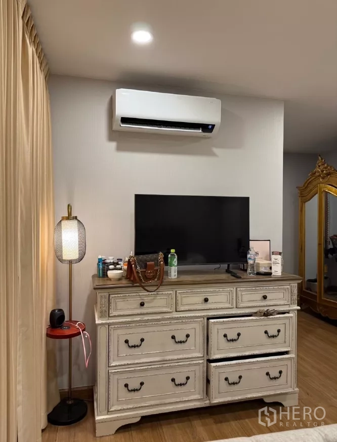 Detached House for rent or sale in Saphan Sung, Bangkok - Bedroom corner with dresser, TV and wall-mounted air conditioner.