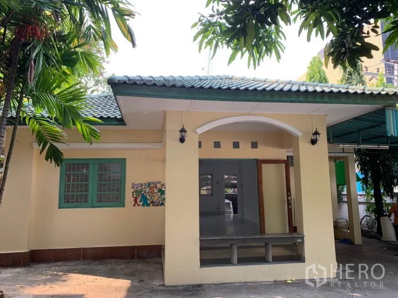 独立式住宅 出租在Khlong Toei, Bangkok - 单层独栋住宅，绿色瓦顶，带顶门廊与热带树木。