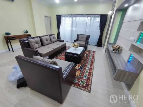 公寓 出租在Khlong Toei, Bangkok - President Park公寓宽敞客厅，皮质沙发组、带层架电视背景墙、花纹地毯与大窗帘窗。