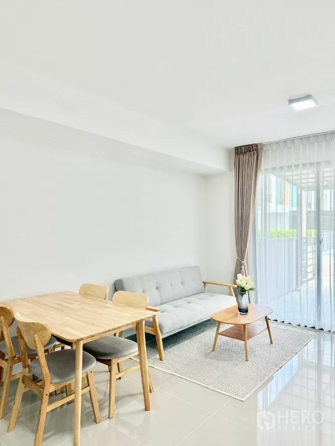 联排别墅 出租在Bang Phli, Samut Prakan - 餐桌与沙发相邻，落地窗让客厅通透明亮。
