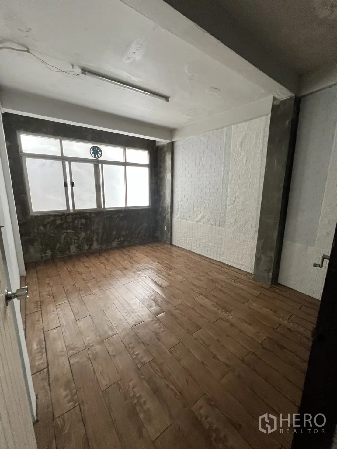 Shophouse for rent in Watthana, Bangkok - Compact office room with wood-look tiles and frosted window.