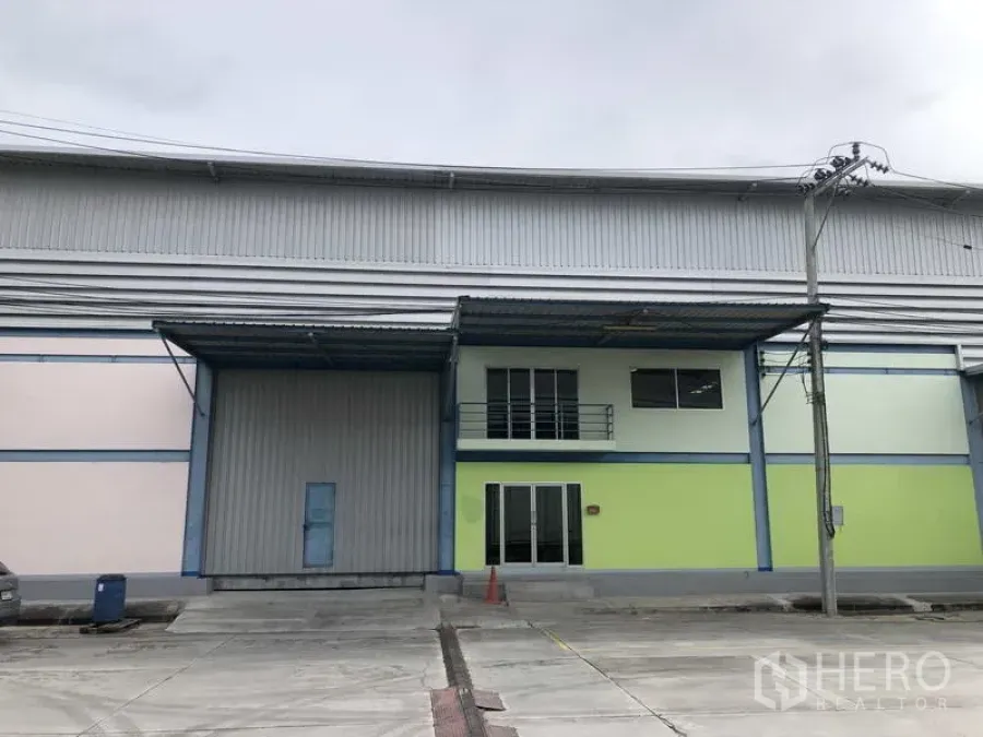 Warehouse for rent in Bang Phli, Samut Prakan - Modern warehouse exterior with large loading door, covered canopy and two‑storey office facade.
