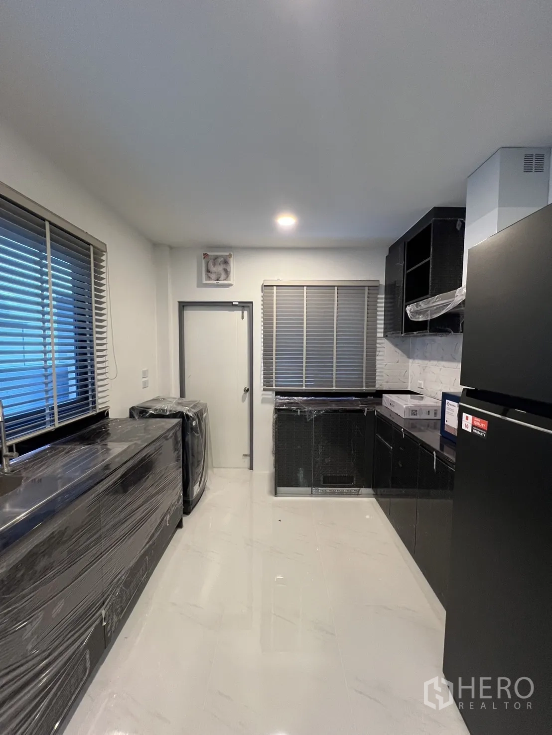 Detached House for rent or sale in Bang Phli, Samut Prakan - Enclosed kitchen with black cabinetry, glossy floors and wrapped new appliances.