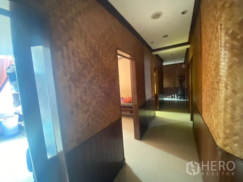 Office Space for rent in Khlong Toei, Bangkok - Hallway with woven wall panels and recessed lights leading to private rooms.