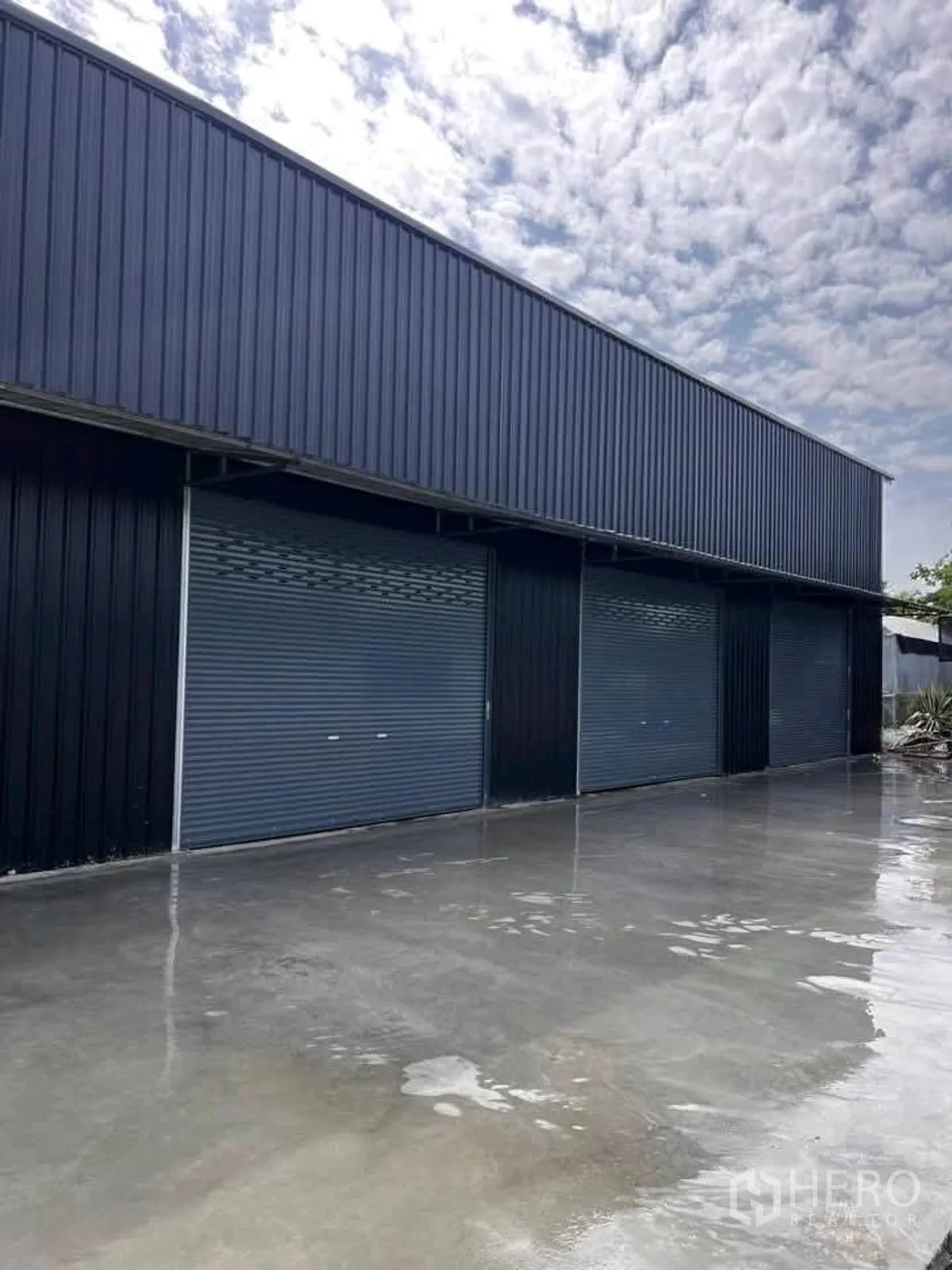 Warehouse for rent in Lat Krabang, Bangkok - Warehouse exterior with several roller shutter doors and a wide concrete yard.