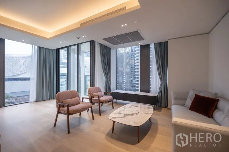 Condominium for rent in Pathum Wan, Bangkok - Living and dining area with recessed lighting, pale wood floors and expansive windows.