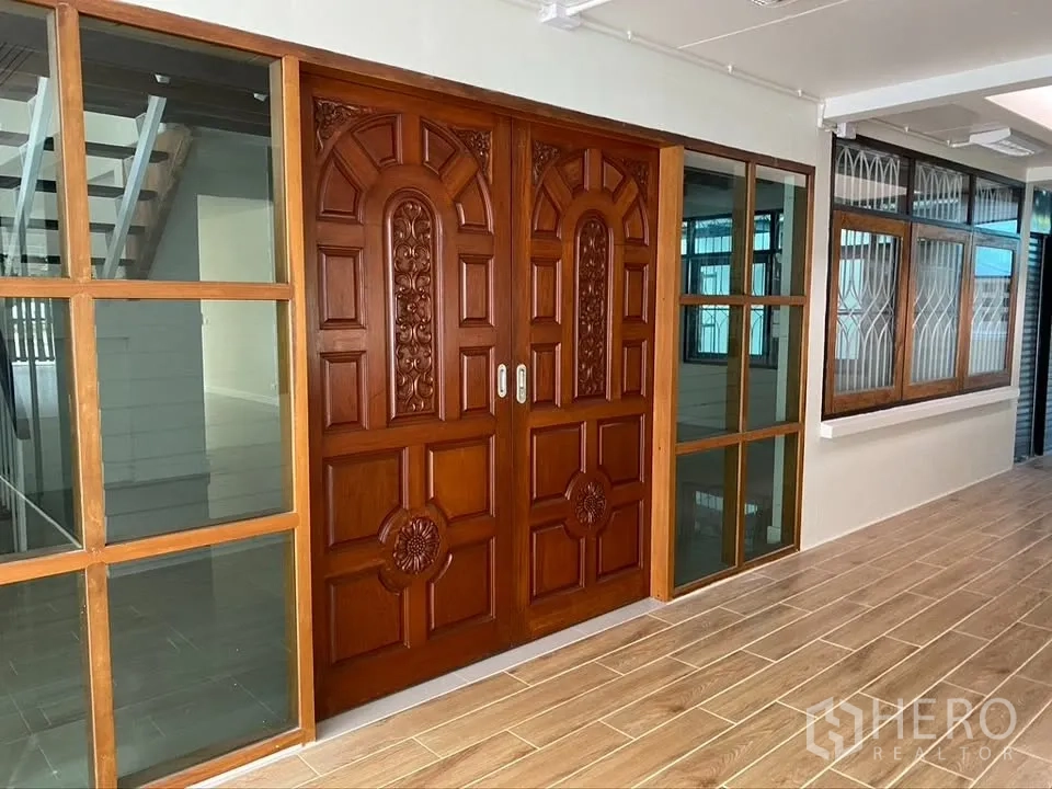 Detached House for rent in Suan Luang, Bangkok - Close-up of carved wooden double entrance doors with side glass panels.