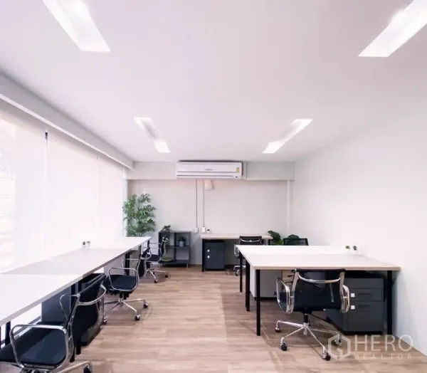Office Space for rent in Bang Rak, Bangkok - Bright open-plan office with long work desks, swivel chairs, wood flooring, and air-conditioning.
