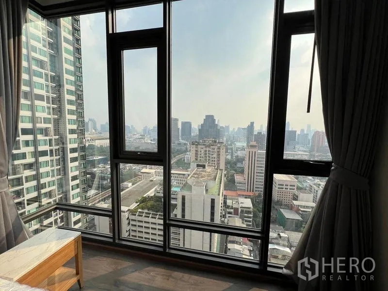 Condominium for rent in Ratchathewi, Bangkok - Corner bedroom with wraparound windows and curtains overlooking downtown Bangkok.