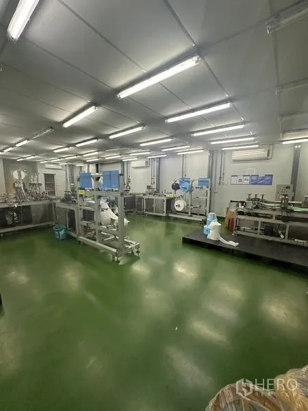 Warehouse for rent or sale in Lam Luk Ka, Pathum Thani - Another angle of machinery and workstations on a green epoxy floor.
