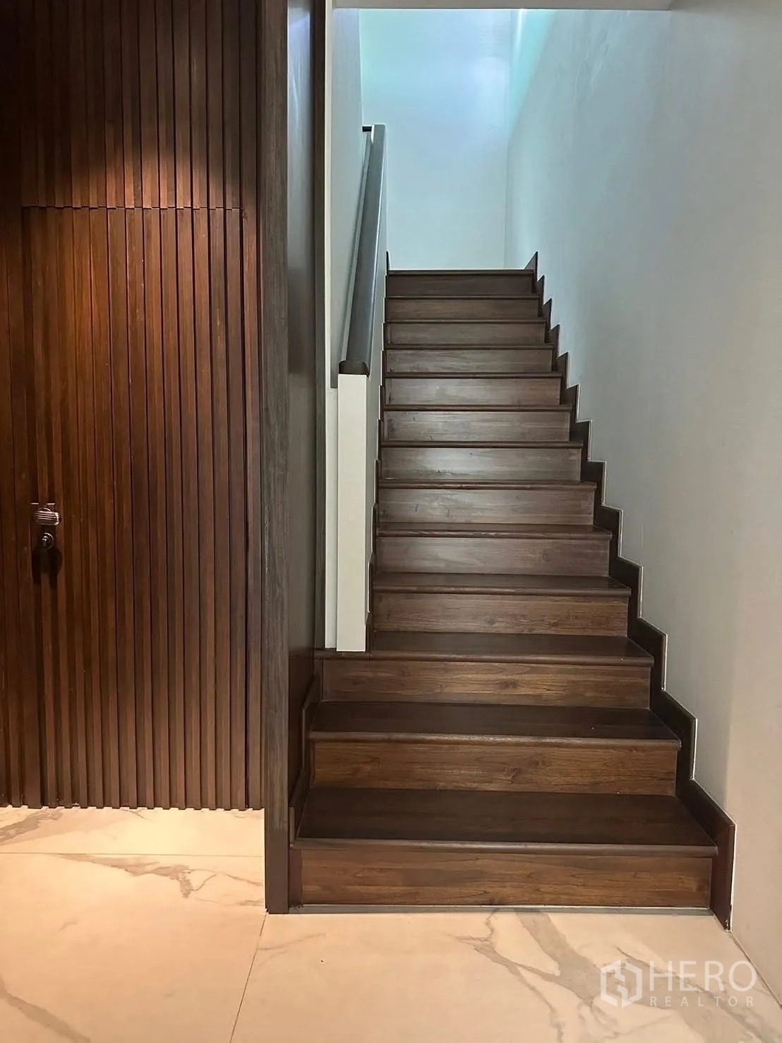 独立式住宅 出租在Lat Krabang, Bangkok - 木质楼梯与大理石纹地面，旁有竖向木饰面墙。