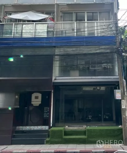 Retail Space for rent in Watthana, Bangkok - Street-facing shophouse exterior with glass storefront and raised turf steps in Bangkok.