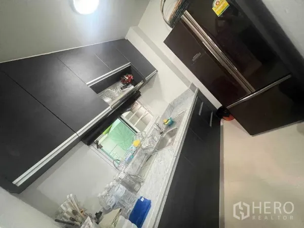 Townhouse for rent in Bueng Kum, Bangkok - Galley kitchen with dark cabinetry, marble countertop and large fridge.