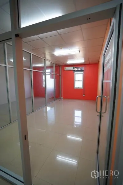 Factory for sale in Khlong Luang, Pathum Thani - Glass meeting room with orange accent wall and wall-mounted air conditioner.