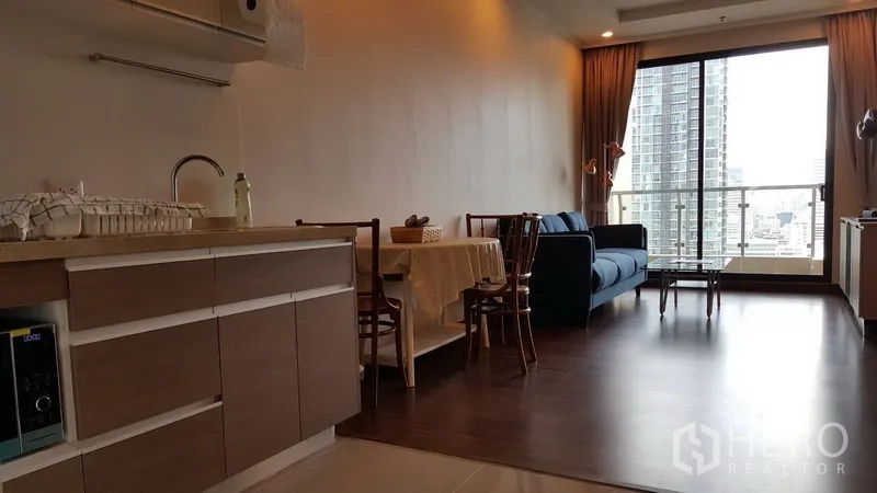 คอนโด ให้เช่าในSathon, Bangkok - ห้องนั่งเล่นแบบโอเพ่นพร้อมครัวเล็ก ชุดทานอาหาร โซฟาสีน้ำเงิน และระเบียงมองเห็นสกายไลน์สาทร