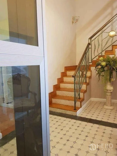 Townhouse for sale in Yan Nawa, Bangkok - Staircase with patterned tile floor, wooden steps and metal handrail, accented by greenery.