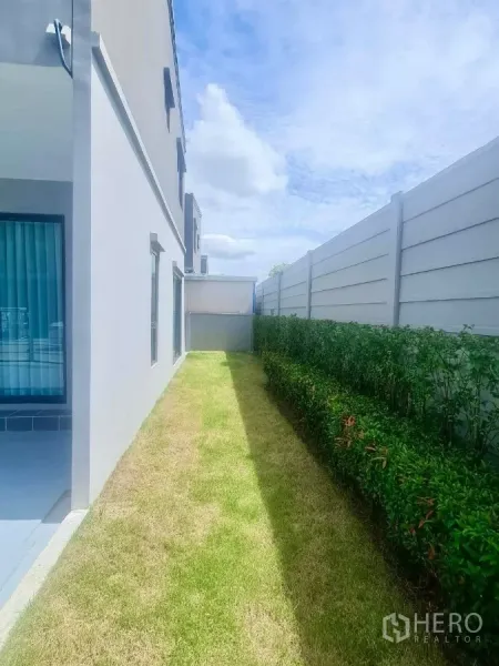 Townhouse for rent in Bang Phli, Samut Prakan - Side lawn running along the house with privacy fence and shrubs.