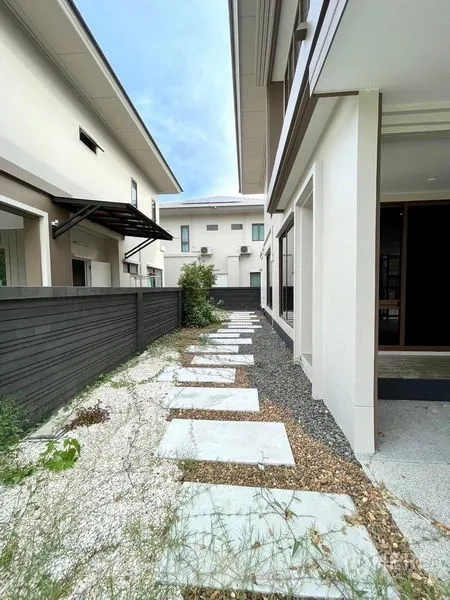 独立式住宅 出售在Bang Kapi, Bangkok - 房屋侧后方石板步道与碎石庭院，配隐私围栏。