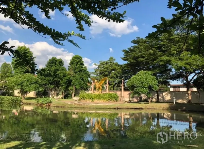 Detached House for rent or sale in Lat Phrao, Bangkok - Community park with pond, trees and blue sky reflections.