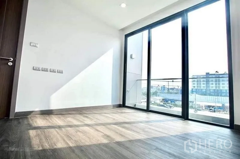 Home Office for rent in Don Mueang, Bangkok - Room with wood flooring opening to a balcony through full-height sliding doors and city outlook.