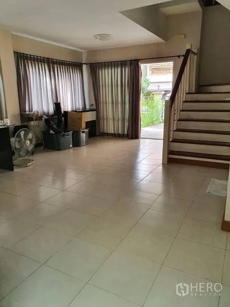 Townhouse for rent in Bueng Kum, Bangkok - Open-plan ground floor with tiled flooring, large windows, and stairs near the front entry.